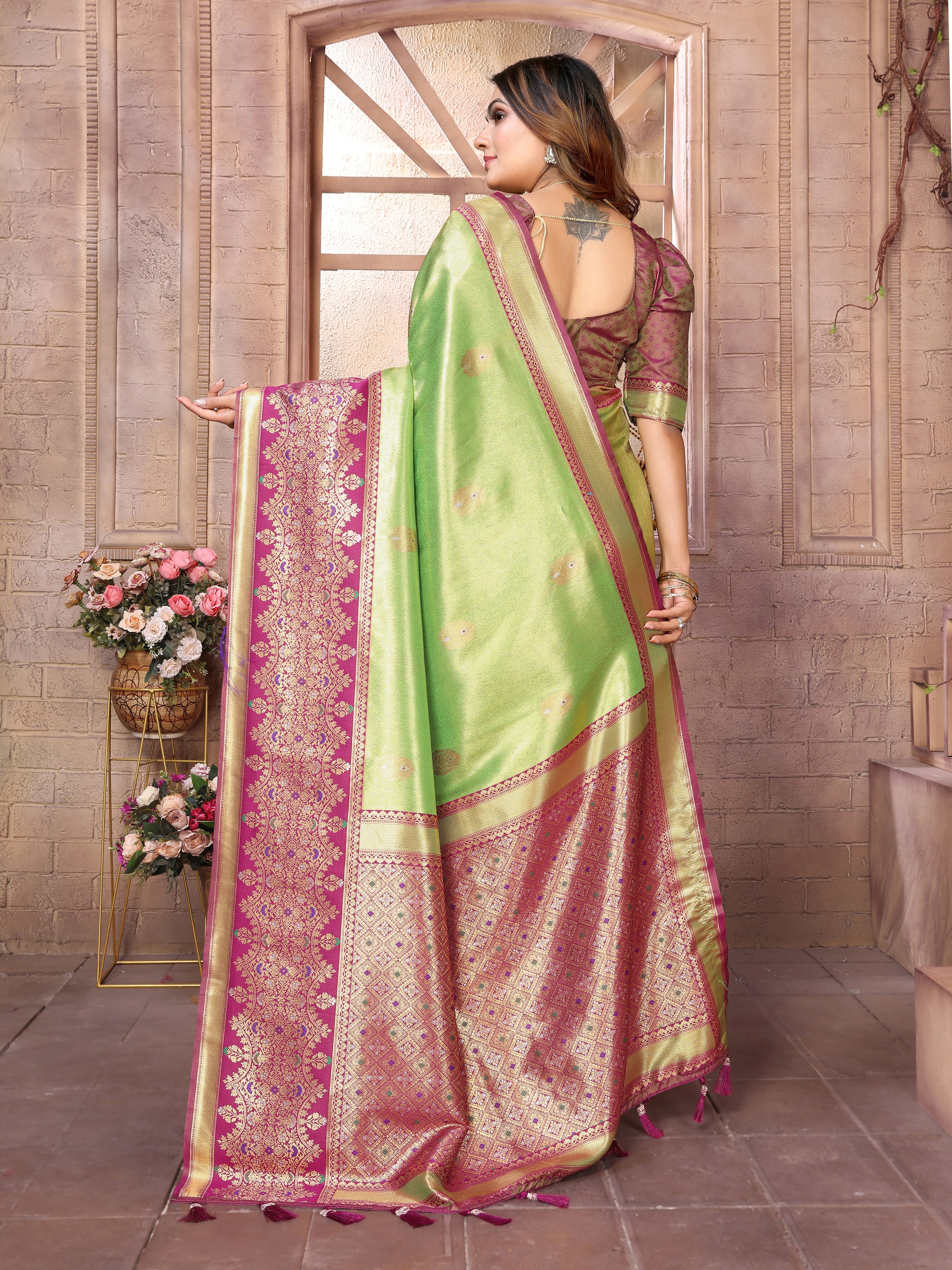 Woman wearing a green and pink saree with a floral background