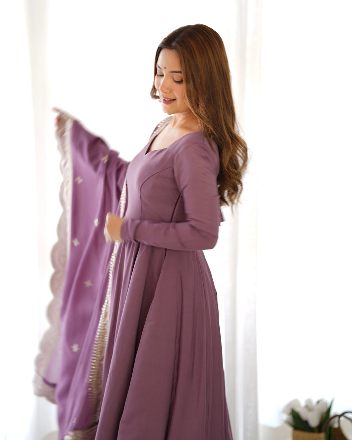 Woman wearing a long purple dress with a white background