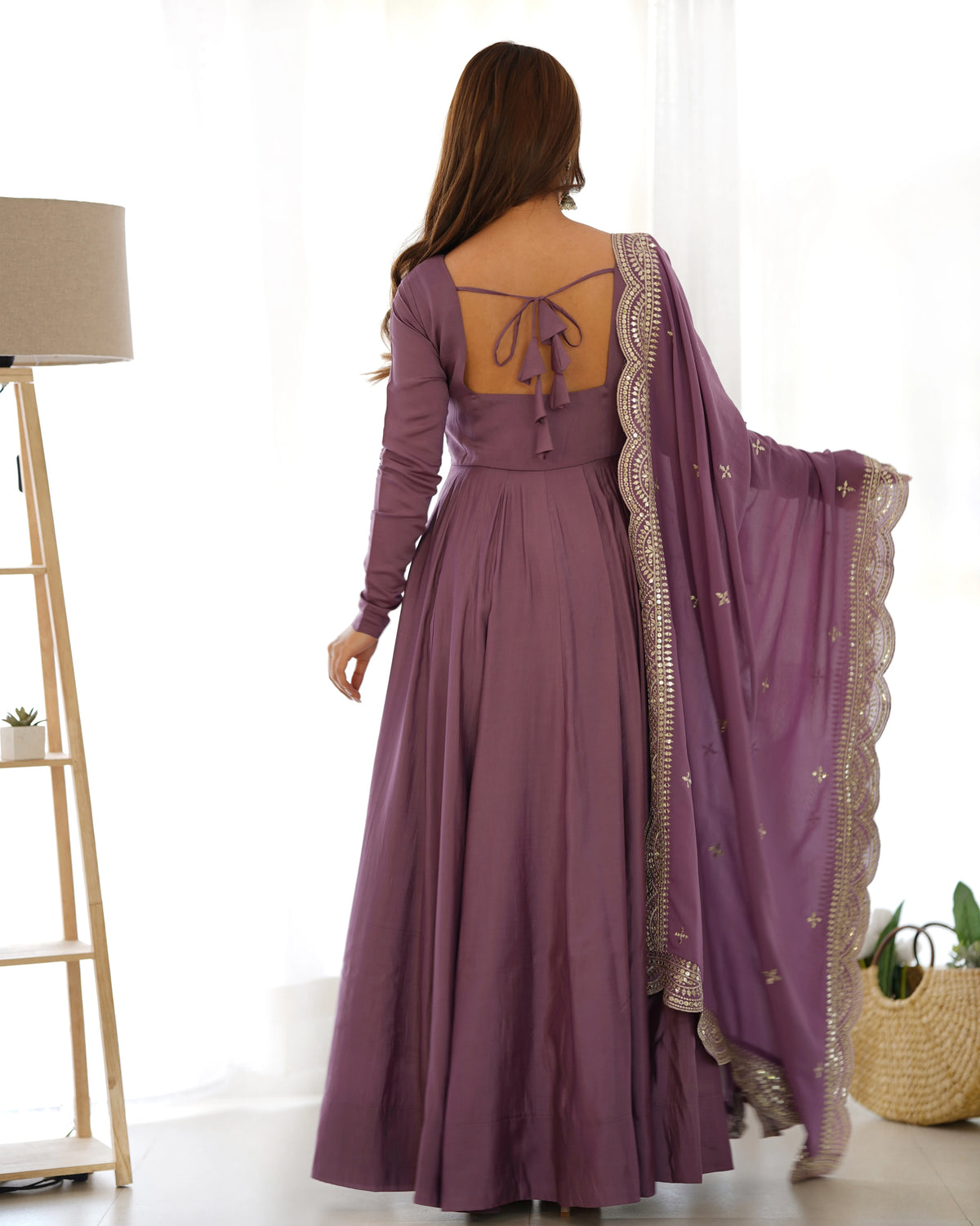 Woman wearing a long purple dress with a matching shawl indoors.