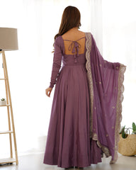 Woman wearing a long purple dress with a matching shawl indoors.
