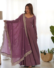 Woman wearing a long purple dress with a matching dupatta in a bright room.
