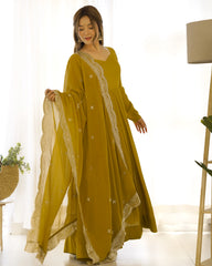 Woman wearing a mustard yellow dress with white embroidery in a bright room.