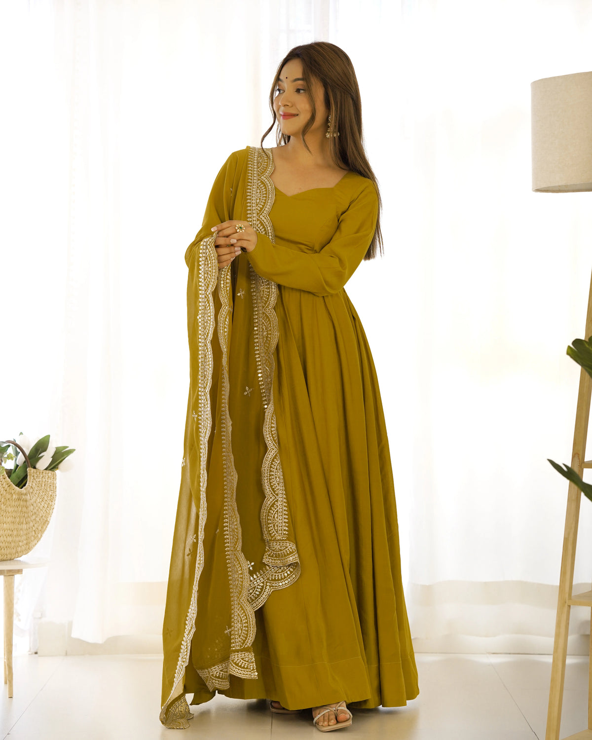 Woman wearing a mustard yellow dress with lace details in a bright room.