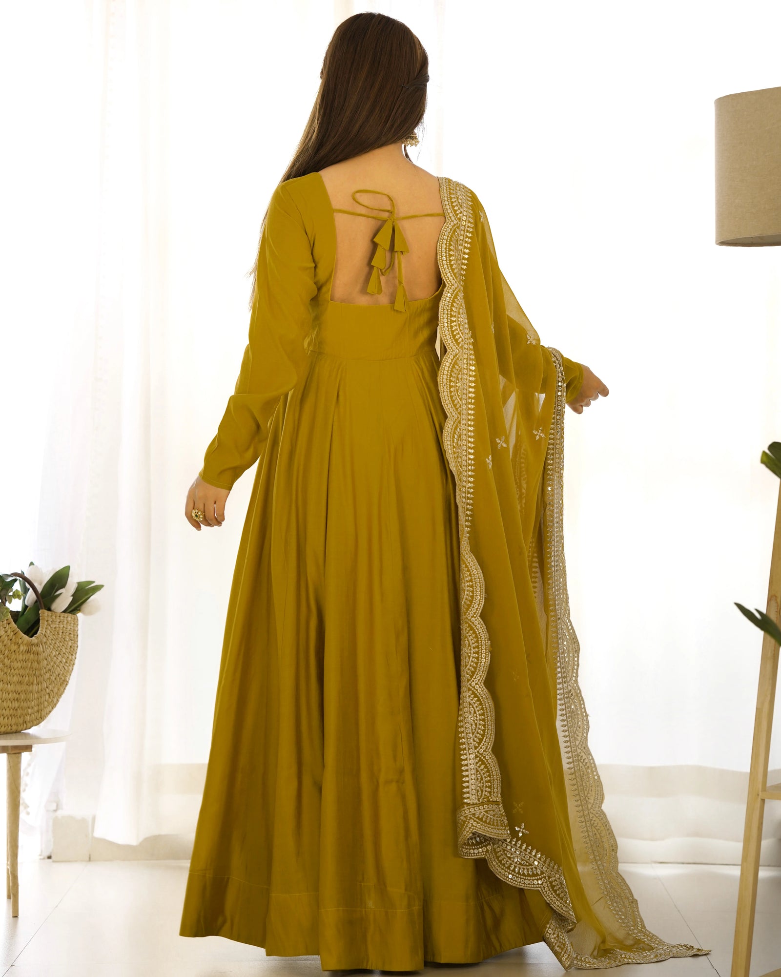 Woman wearing a mustard yellow dress with a matching dupatta in a bright room.