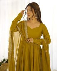 Woman wearing a mustard yellow traditional outfit with a white dupatta against a light background