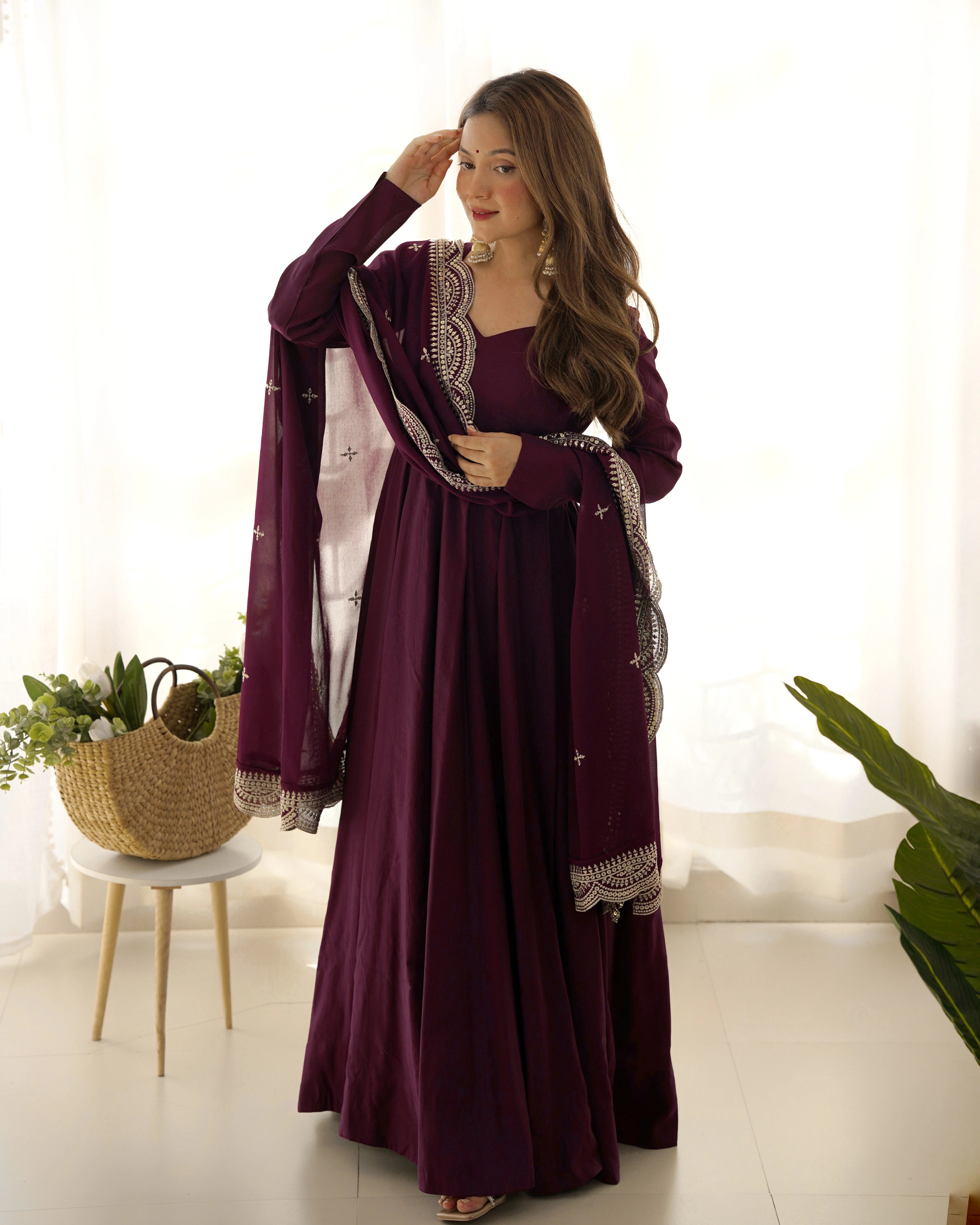 Woman wearing a long purple dress with a matching jacket indoors.
