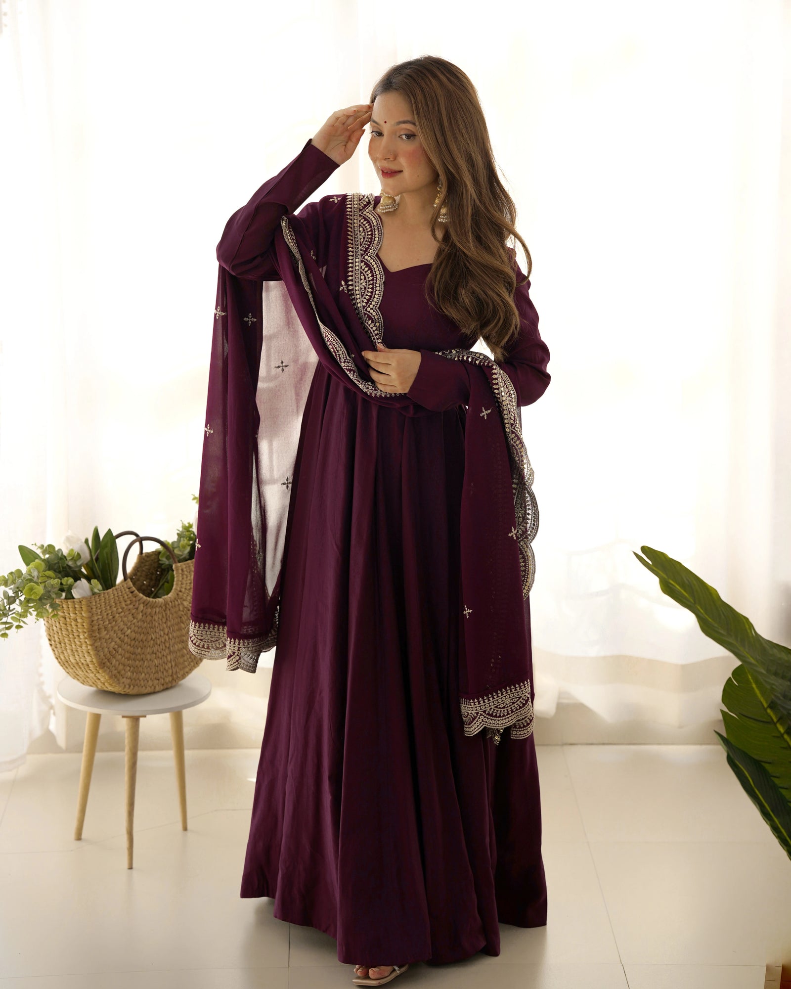 Woman wearing a long purple dress with a matching jacket indoors.