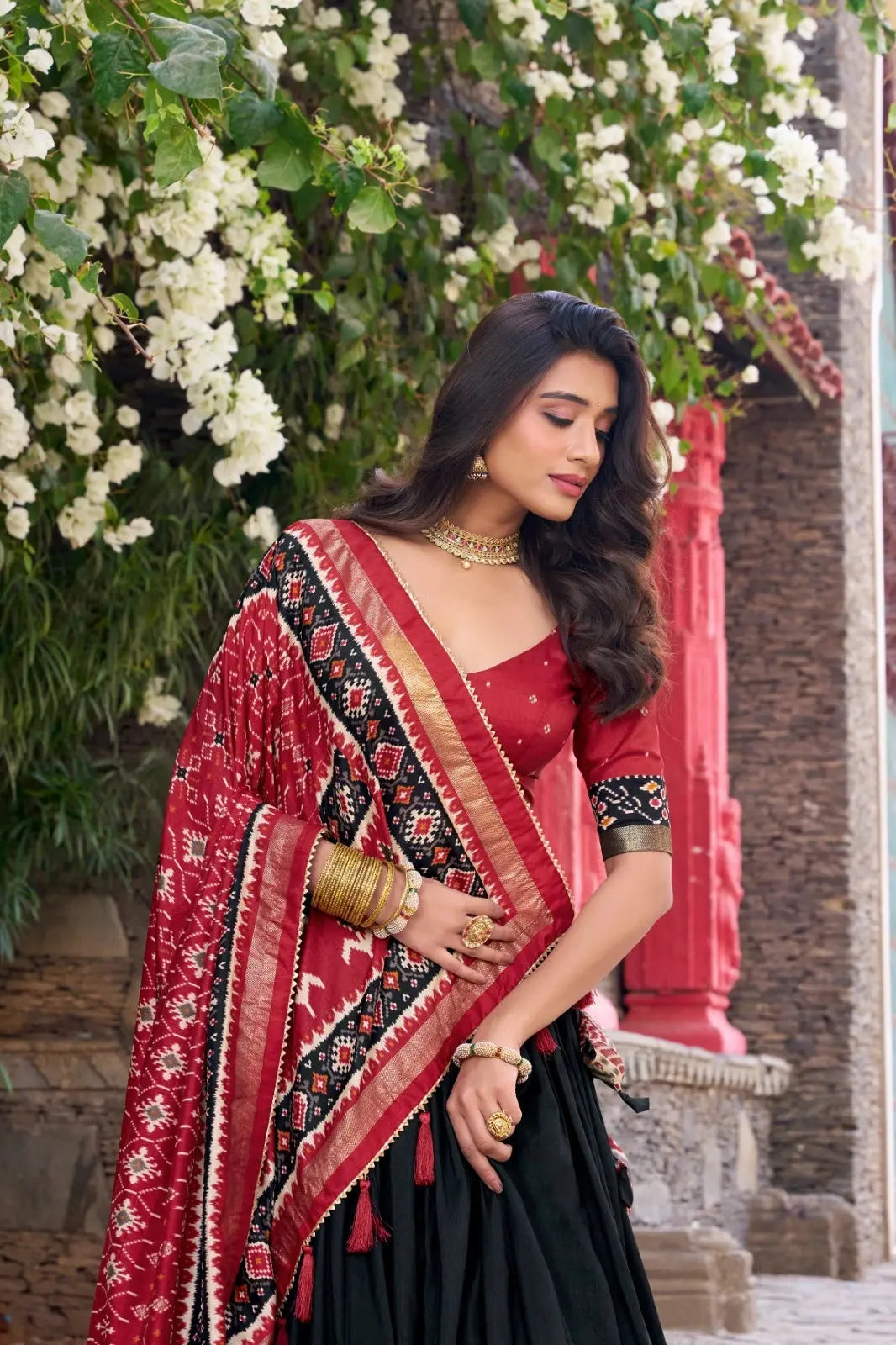 Black Lehenga choli close-up – red V-neck choli with floral butti print, patola dupatta with gold zari border detail
