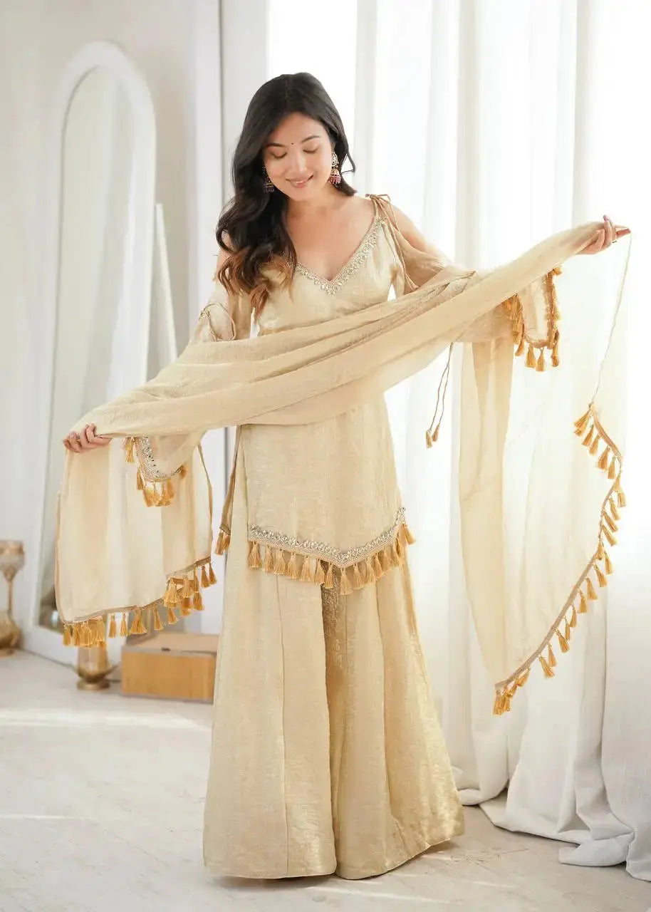 KU212 Beige Suit – Full-length shot with model holding dupatta wide while looking down, showing V-neck detail and bell sleeve tassel cuffs