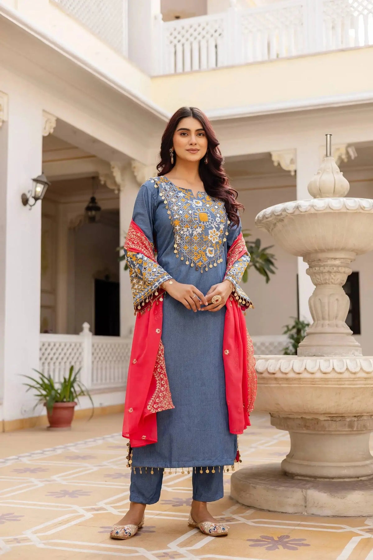 Grayish Blue Heavy Embroidered Suit KU216 with coral-pink Zari Border dupatta draped over shoulder – by fountain