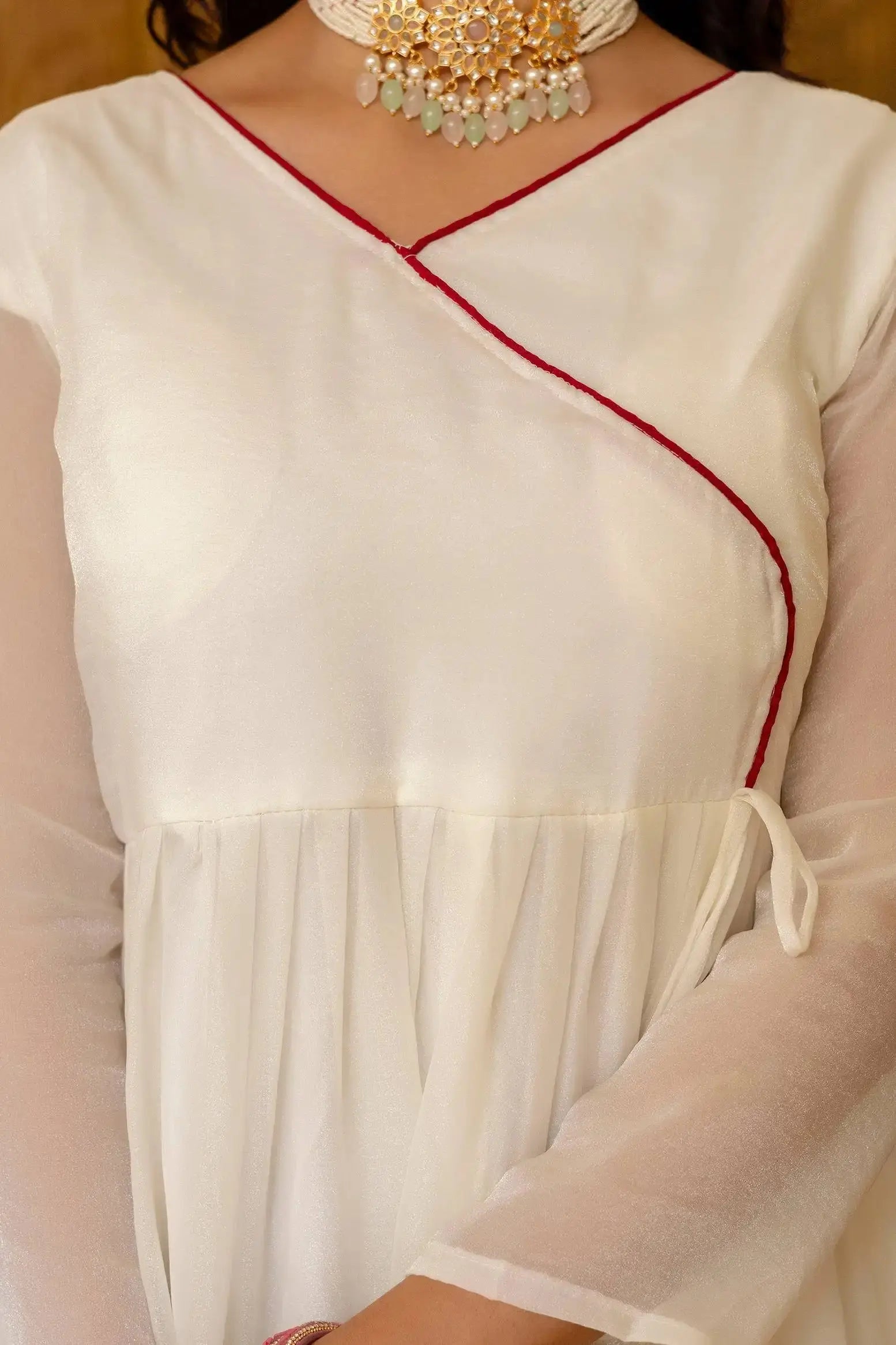 KU217 White Anarkali Suit – Close-up of V-neck with red contrast trim and gold tassel tie-up