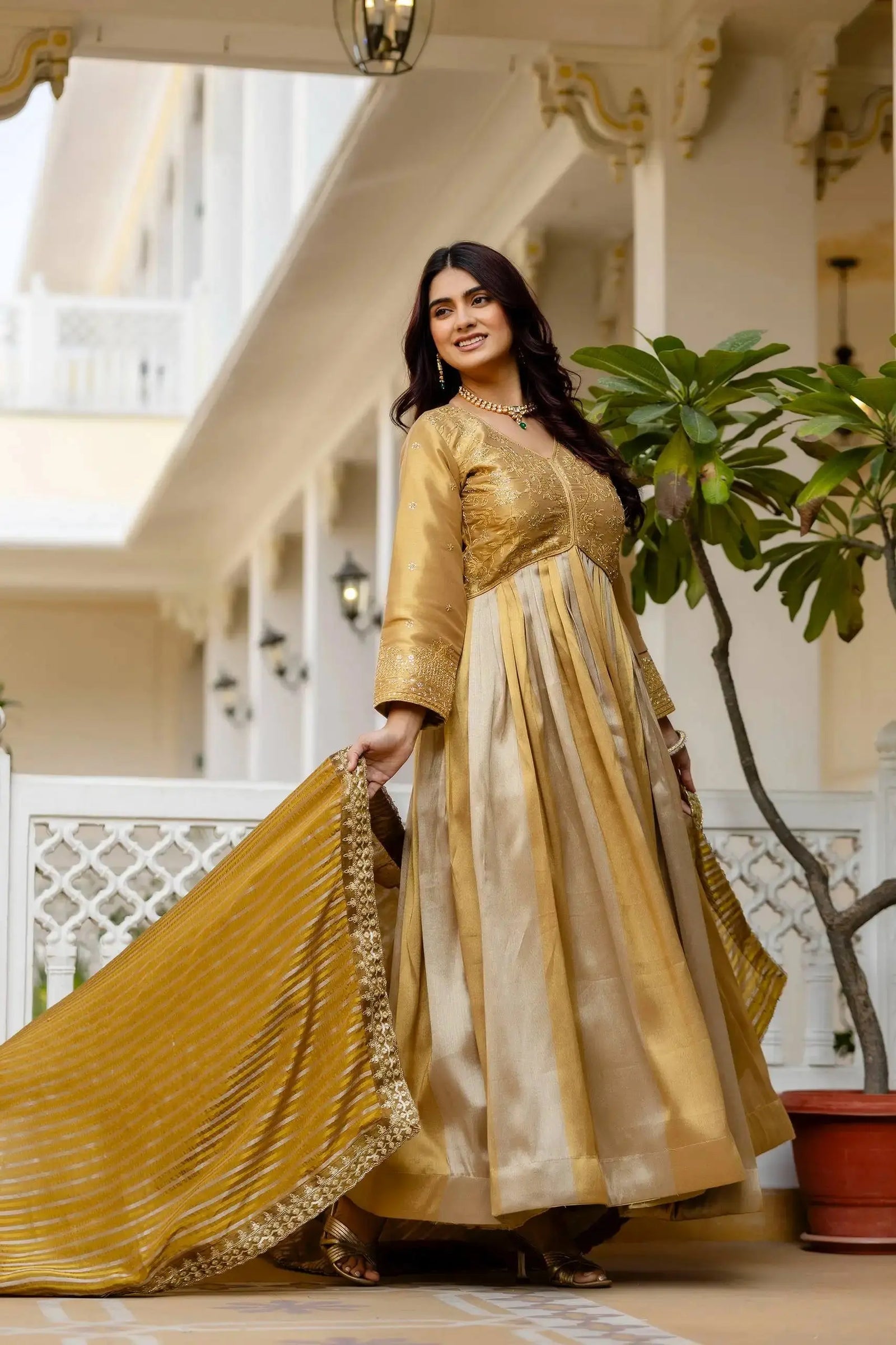 KU218 Beige Anarkali Suit – Three-quarter side view holding mustard striped dupatta with lace border