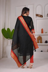 Woman wearing a black saree with red border in a minimalistic setting