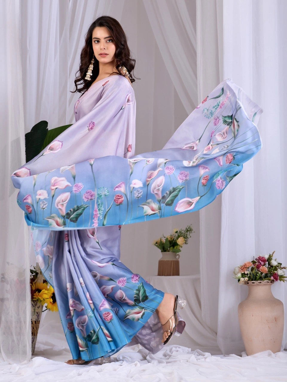 Woman holding a floral saree with a white curtain background