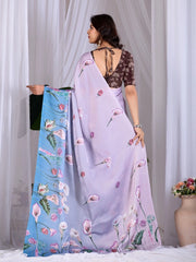 Woman holding a floral saree with a plain blue saree, against a white curtain background.