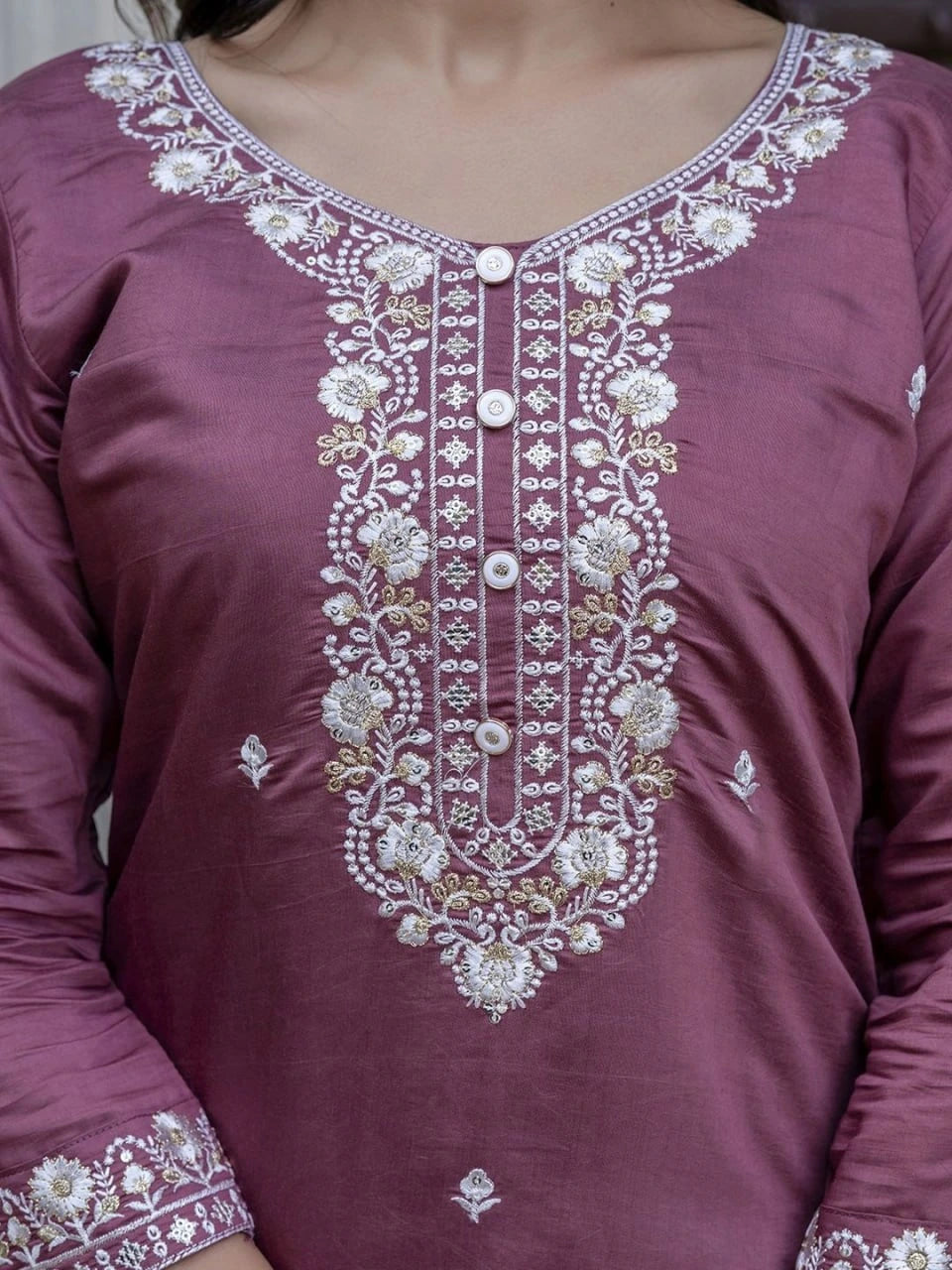 Maroon traditional outfit with intricate white embroidery on a plain background