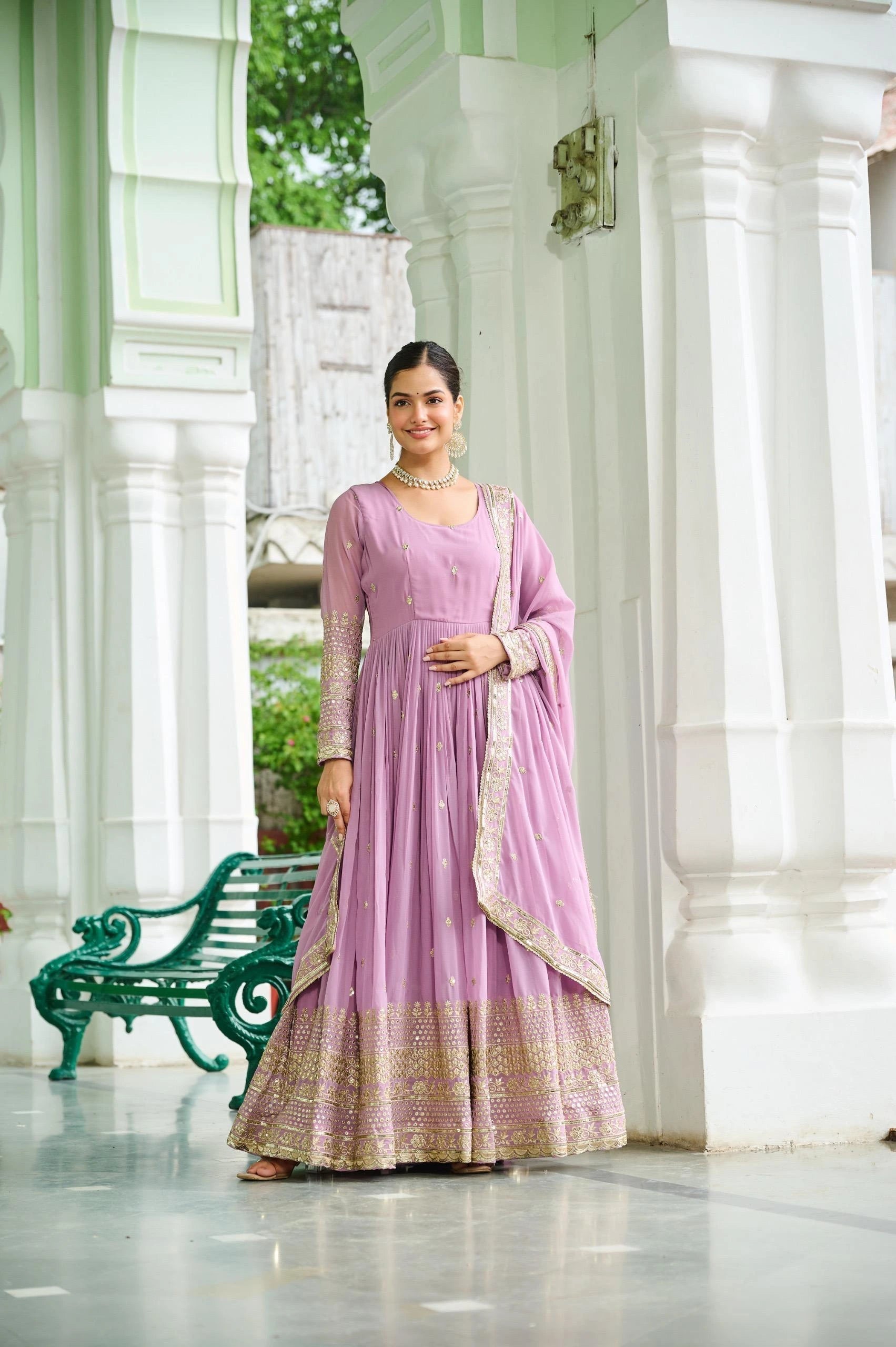 Woman in a pink traditional outfit standing in a white architectural setting.