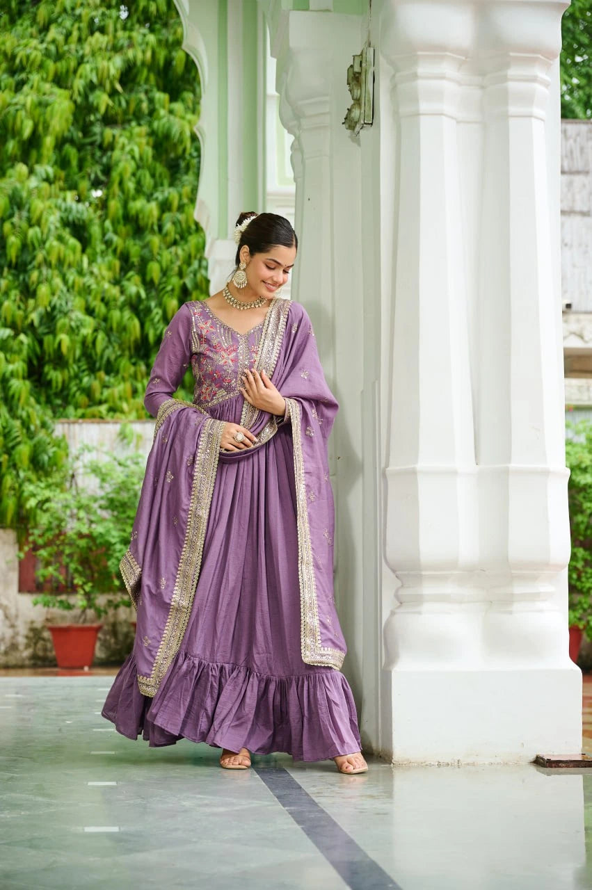 Woman in a purple traditional outfit standing in a garden with white columns.