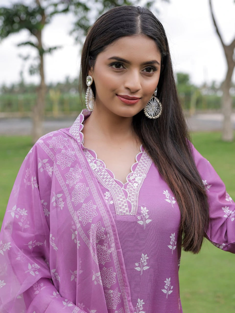 Woman wearing a purple traditional outfit with white embroidery outdoors.