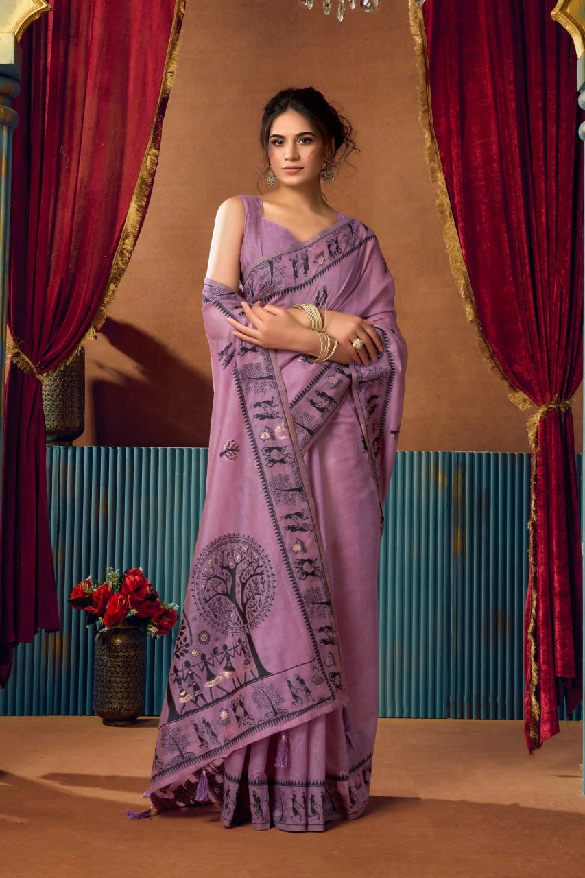 Woman in a purple saree with a decorative pattern standing in front of red curtains.