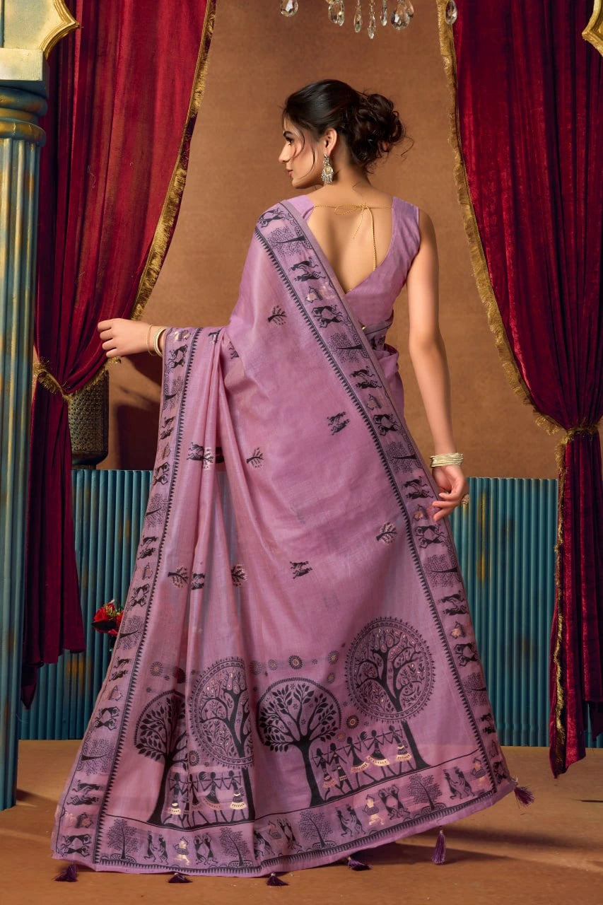 Woman wearing a purple saree with black patterns in a decorative setting.