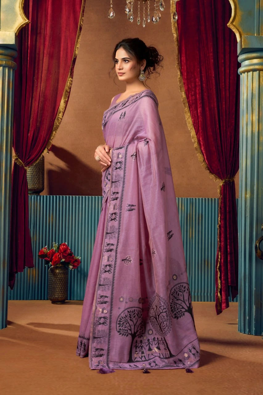 Woman in a purple saree with black patterns standing in front of red curtains.