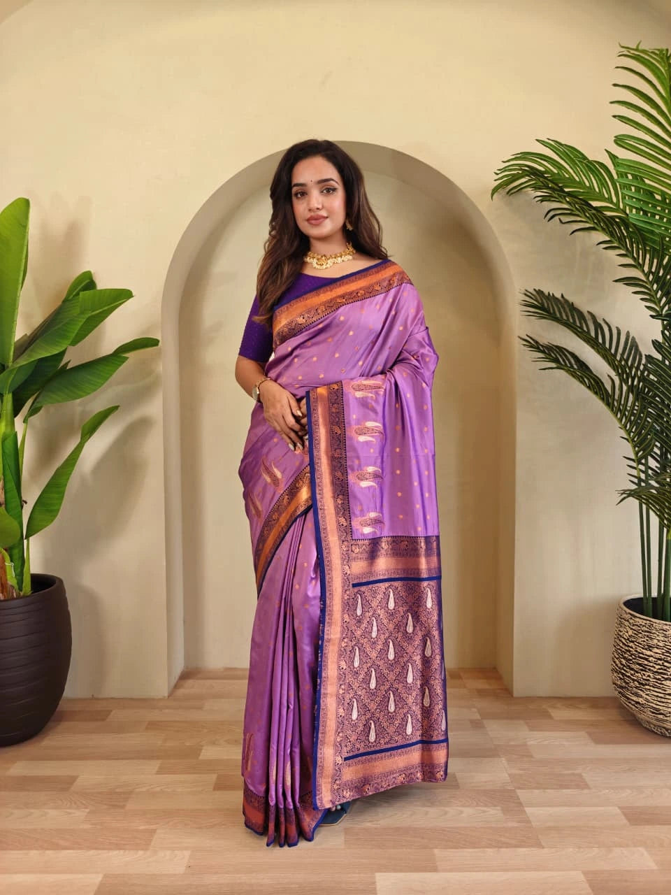 Woman in a purple saree standing in a room with plants