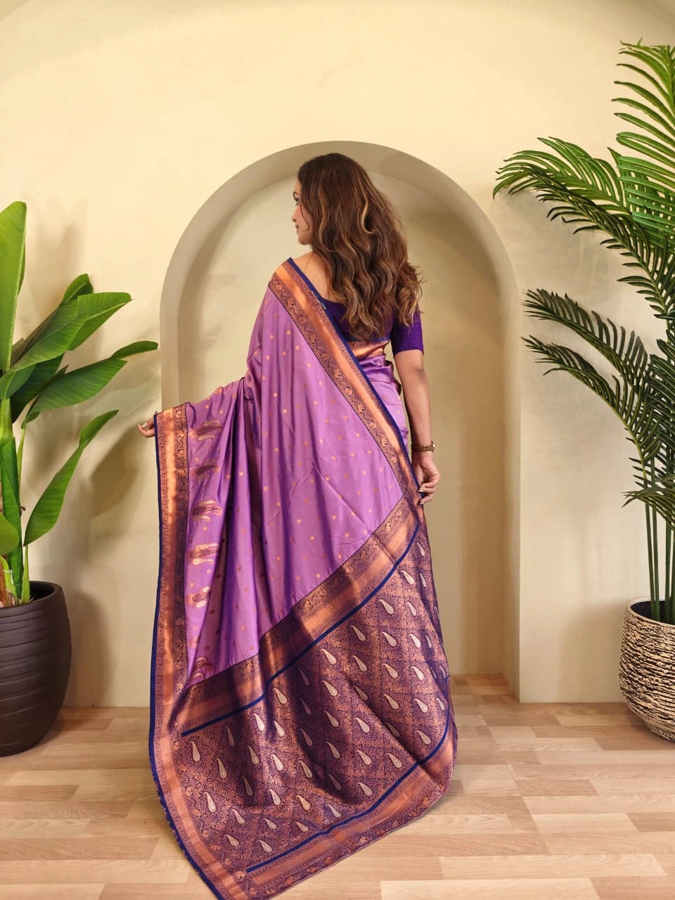 Woman in a purple saree standing in a room with plants