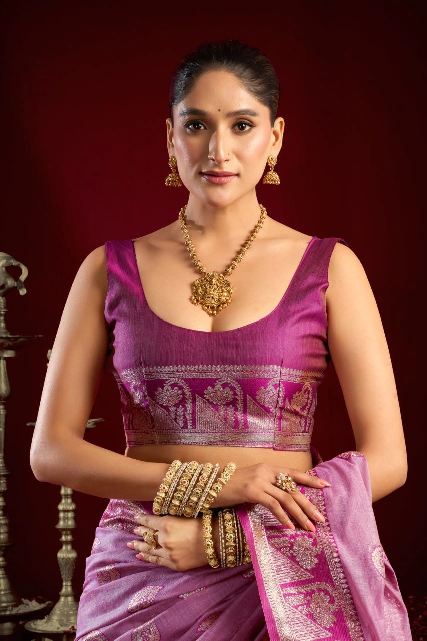 Woman in a traditional pink saree with gold jewelry against a red background