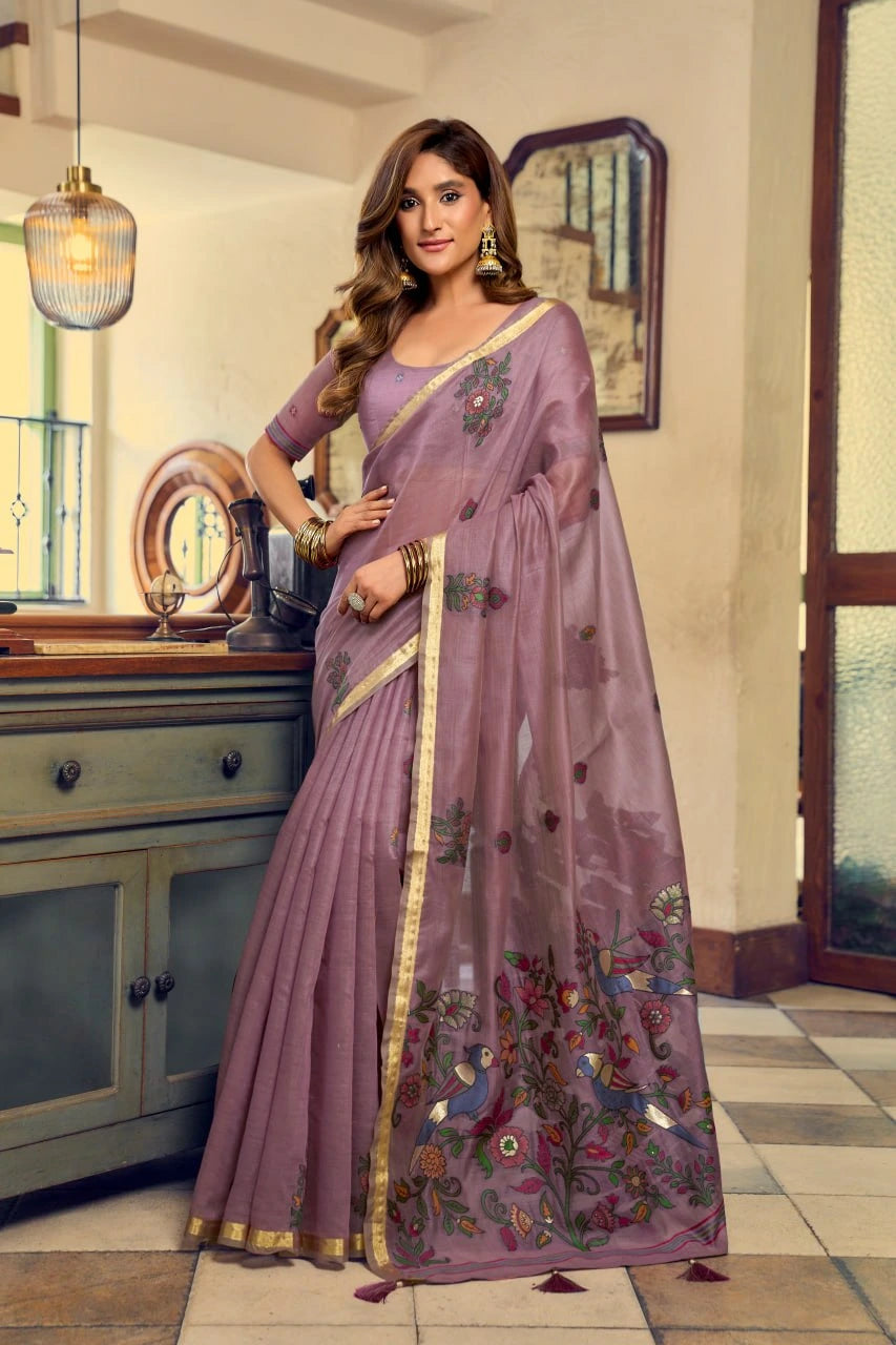 Woman wearing a purple saree with floral patterns in an indoor setting.