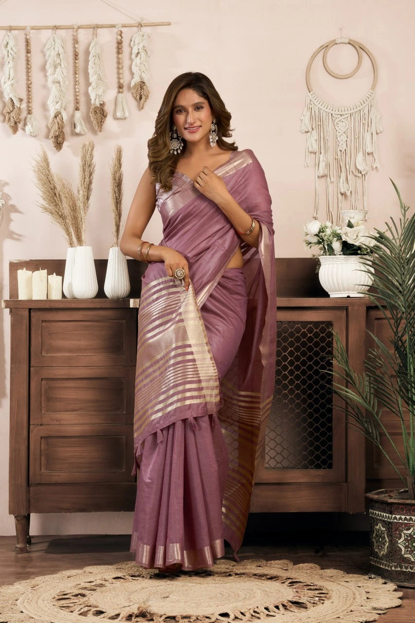 Woman in a purple saree standing in a room with decorative elements.