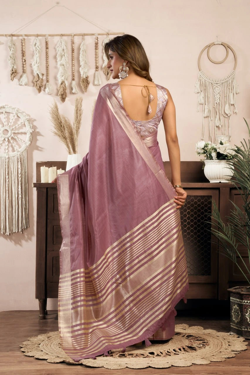 Woman in a mauve saree with a white blouse in a decorated room.