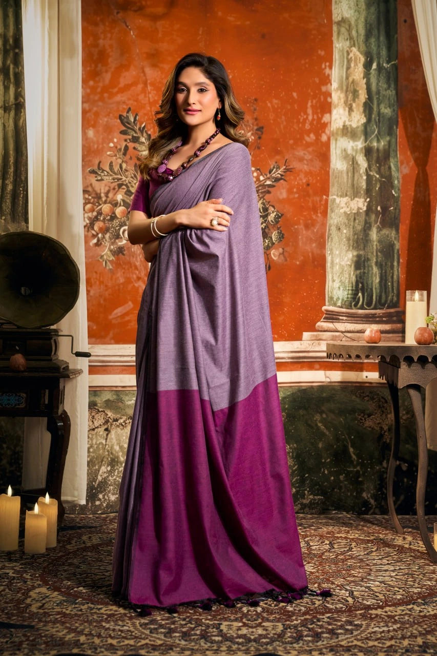 Woman in a purple saree standing in an ornate room with candles and decorative elements.