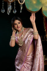 Woman in a pink saree with gold jewelry against a dark background