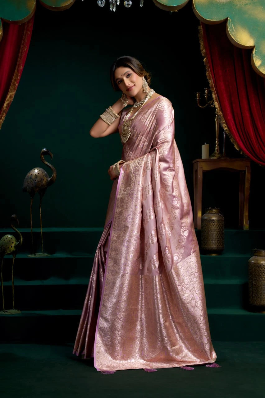 Woman in a pink saree with gold jewelry in a theatrical setting