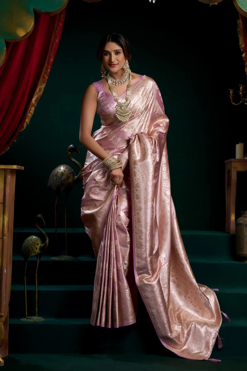 Woman in a pink saree standing in a decorative setting with red curtains and green steps.