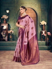 Woman in a traditional saree standing in an elegant interior setting with decorative elements.