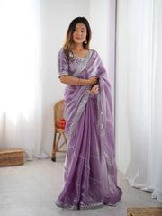 Woman wearing a purple saree with silver border indoors.