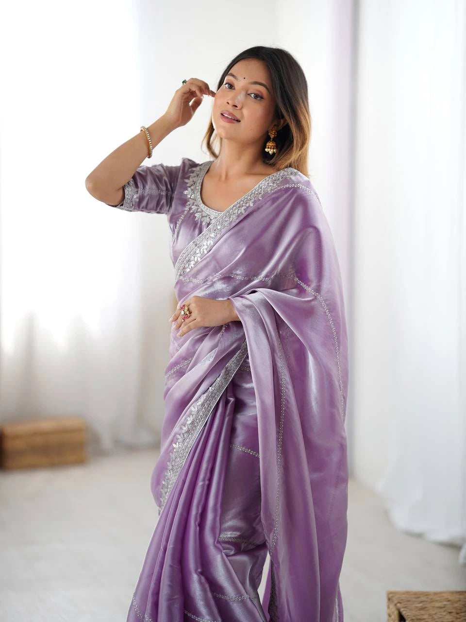 Woman wearing a lavender saree with silver embroidery against a white background