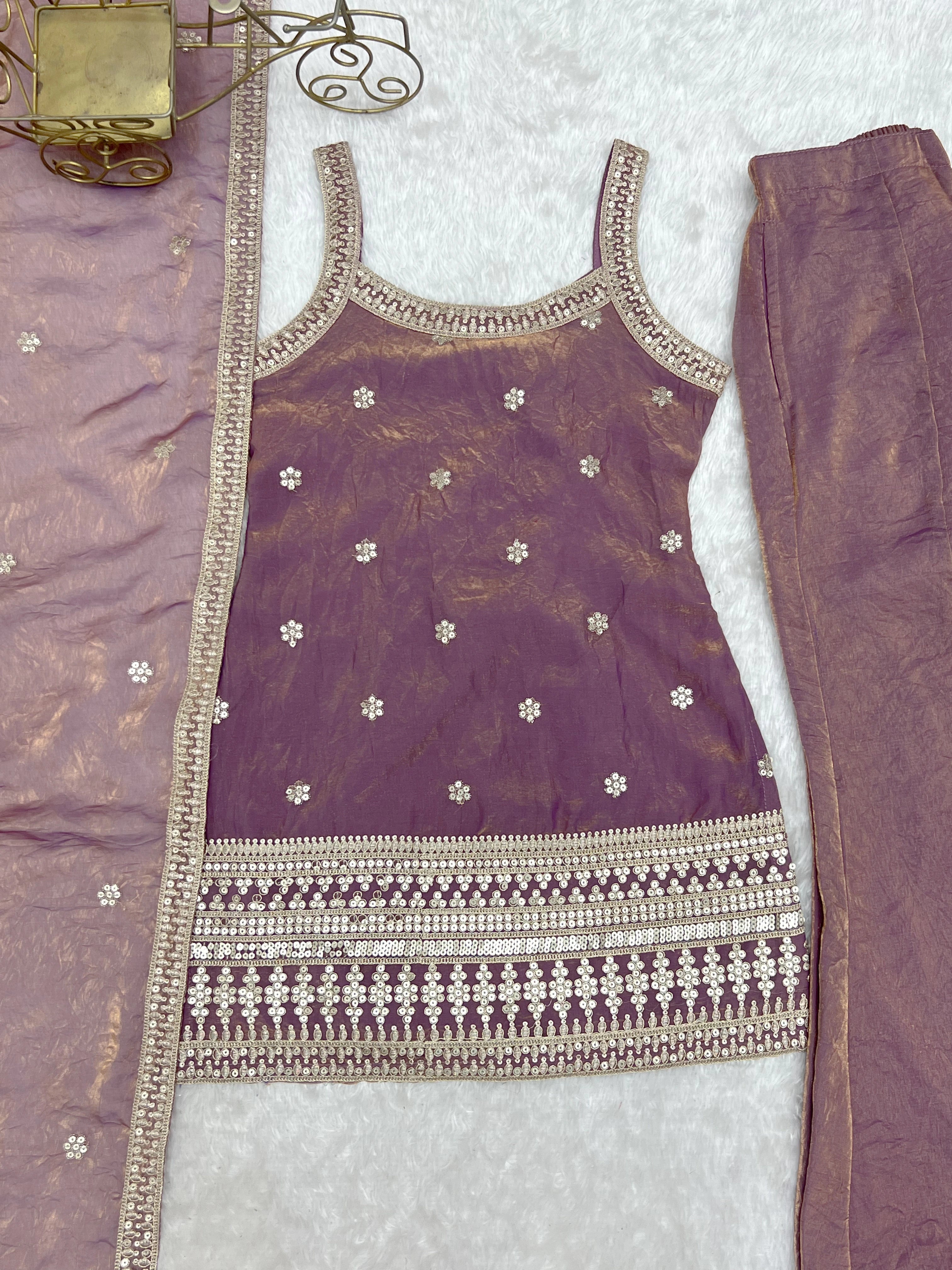 Purple traditional outfit with intricate embroidery on a textured surface
