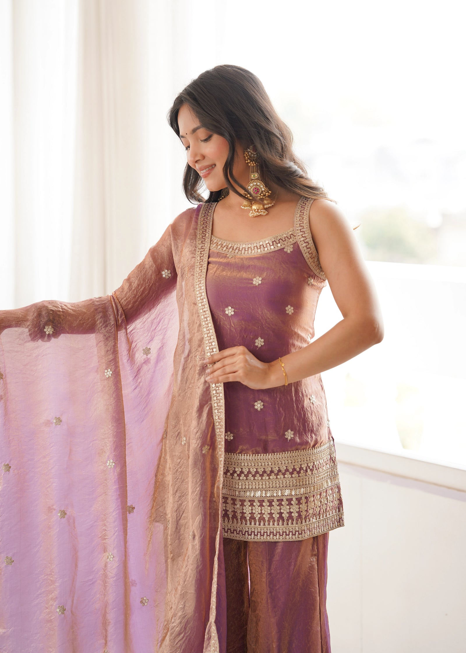 Woman in traditional outfit with a sheer dupatta indoors