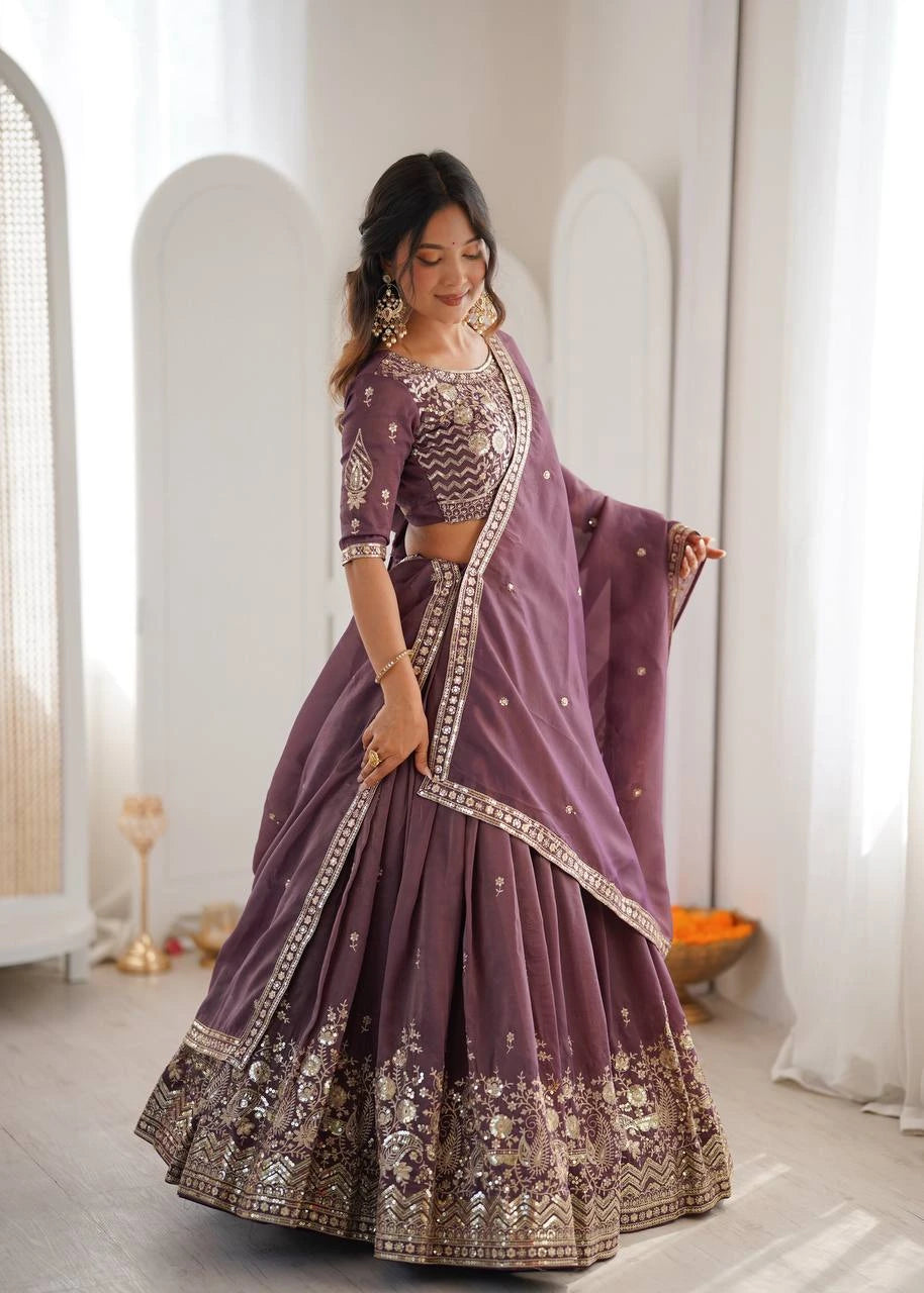 Woman in a purple embroidered traditional outfit standing in a bright room.
