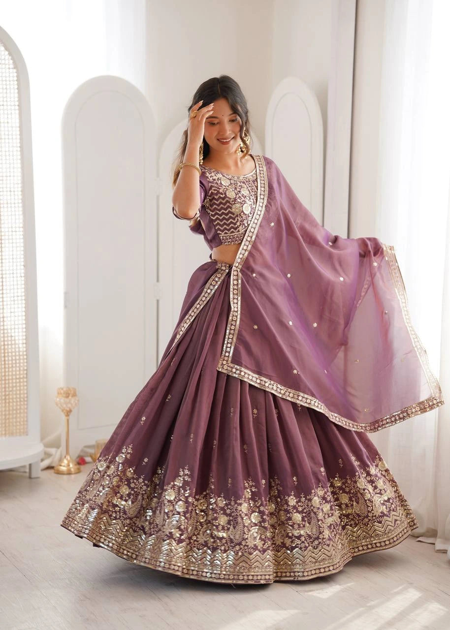 Woman in a purple embroidered traditional outfit standing in a bright room.