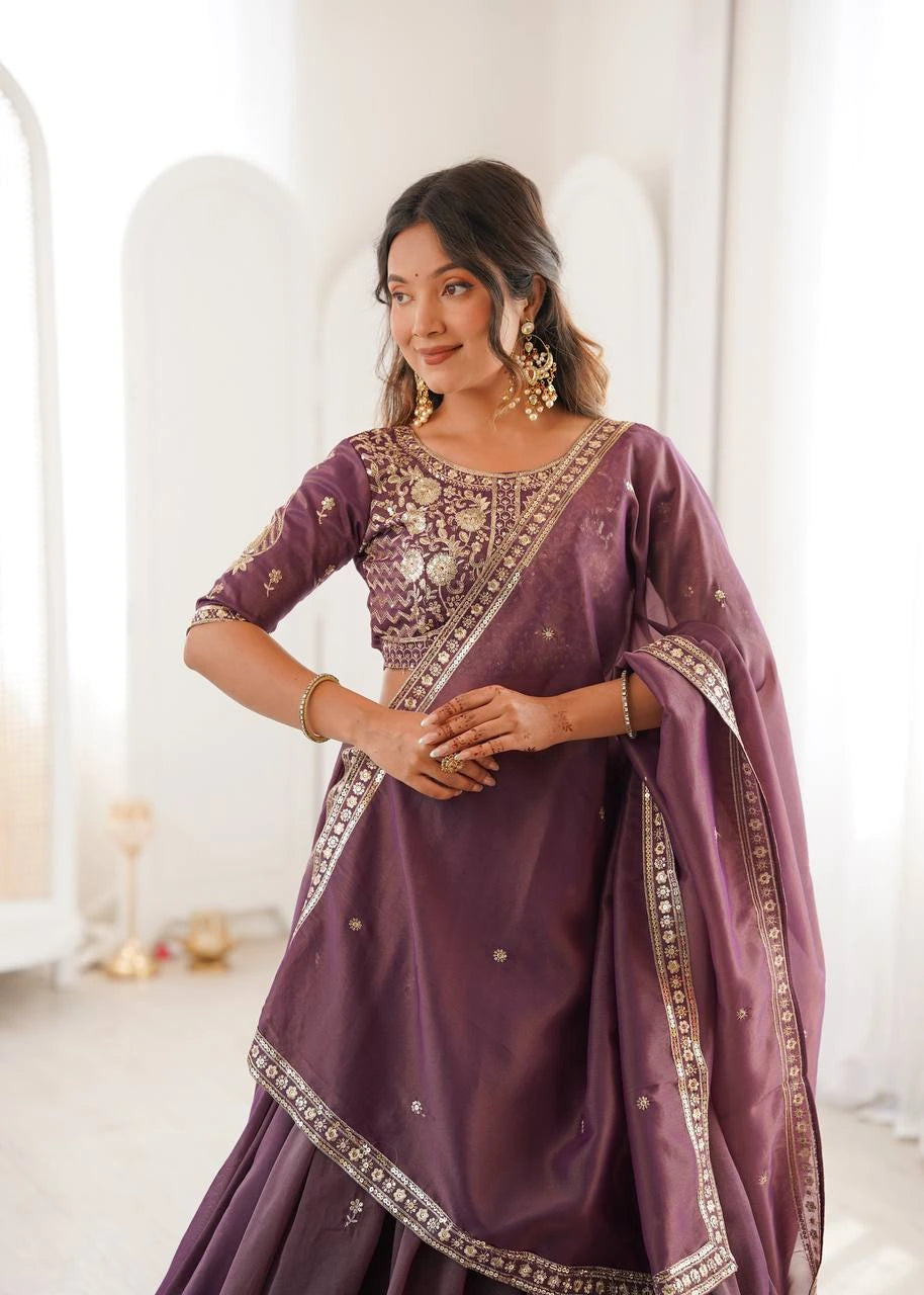 Woman wearing a purple traditional outfit with intricate designs in a bright room.