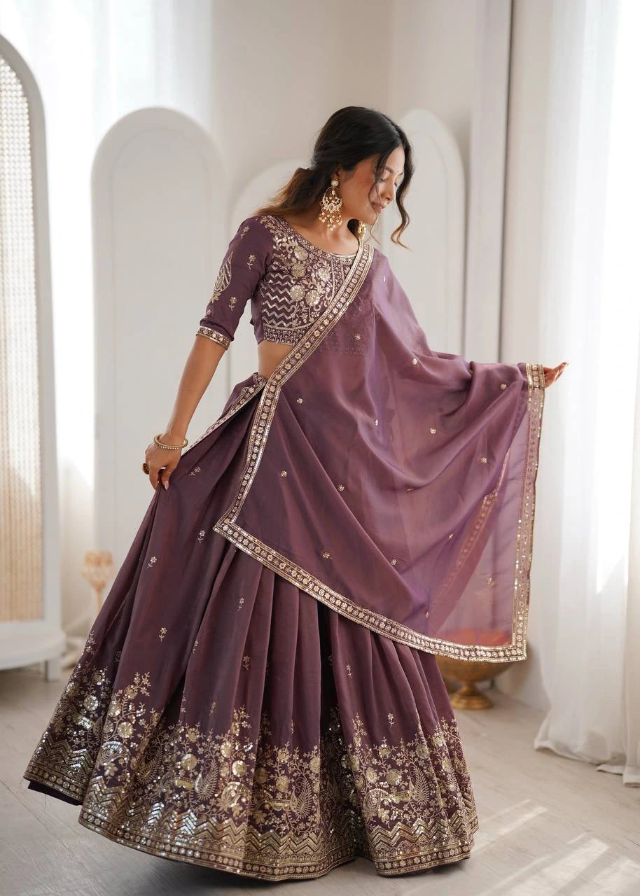 Woman wearing a traditional purple embroidered lehenga in a bright room.