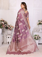 Woman wearing a purple saree with white patterns in a decorated room.