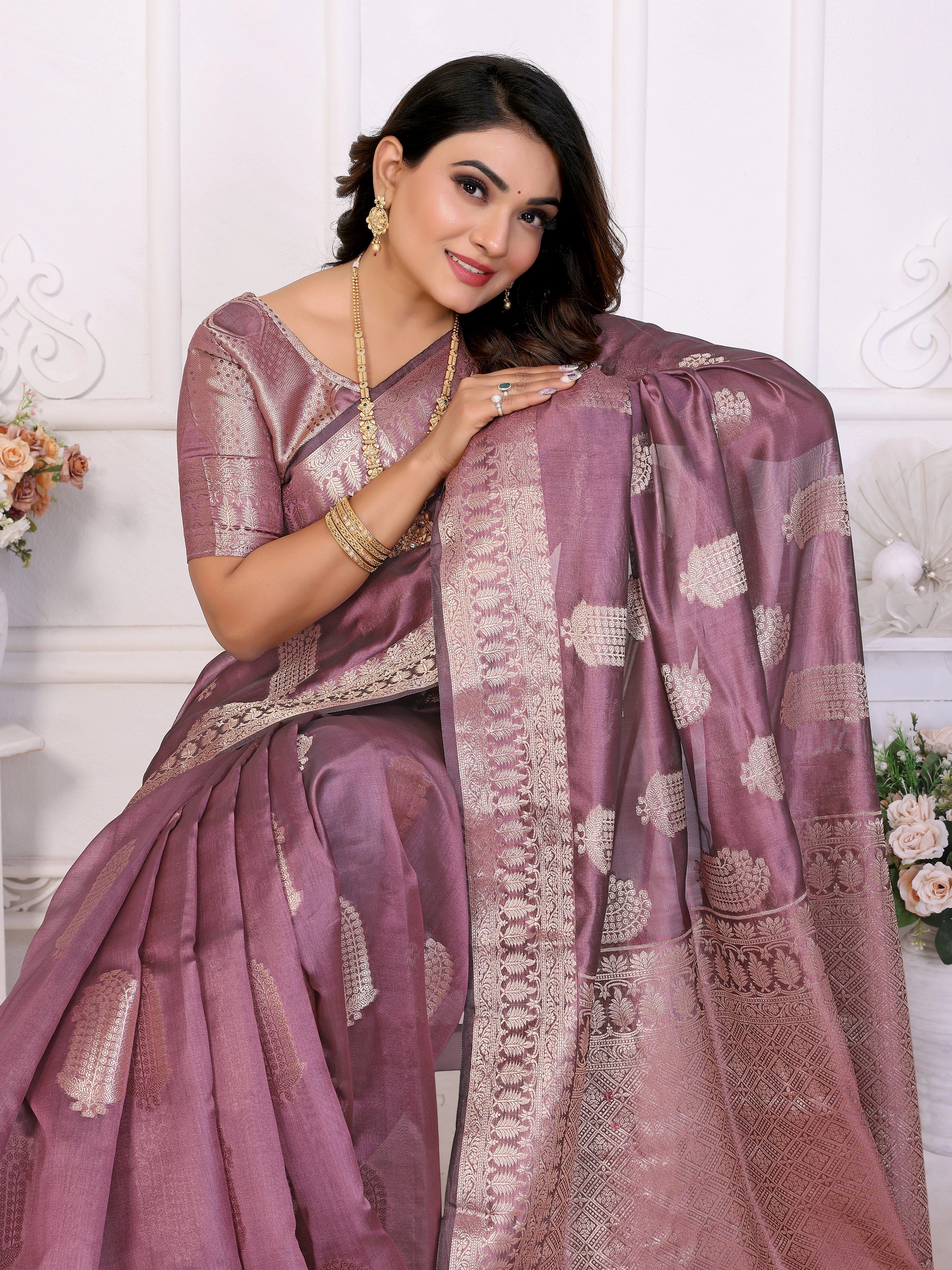 Woman wearing a traditional saree with intricate patterns on a white background