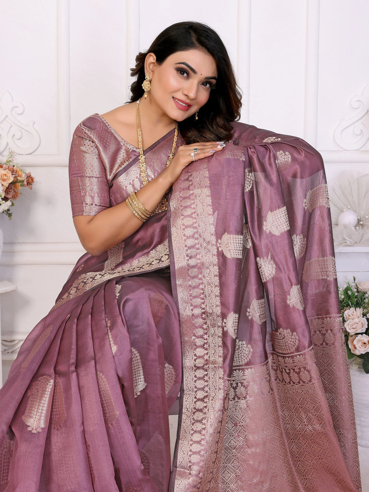 Woman wearing a traditional saree with intricate patterns on a white background