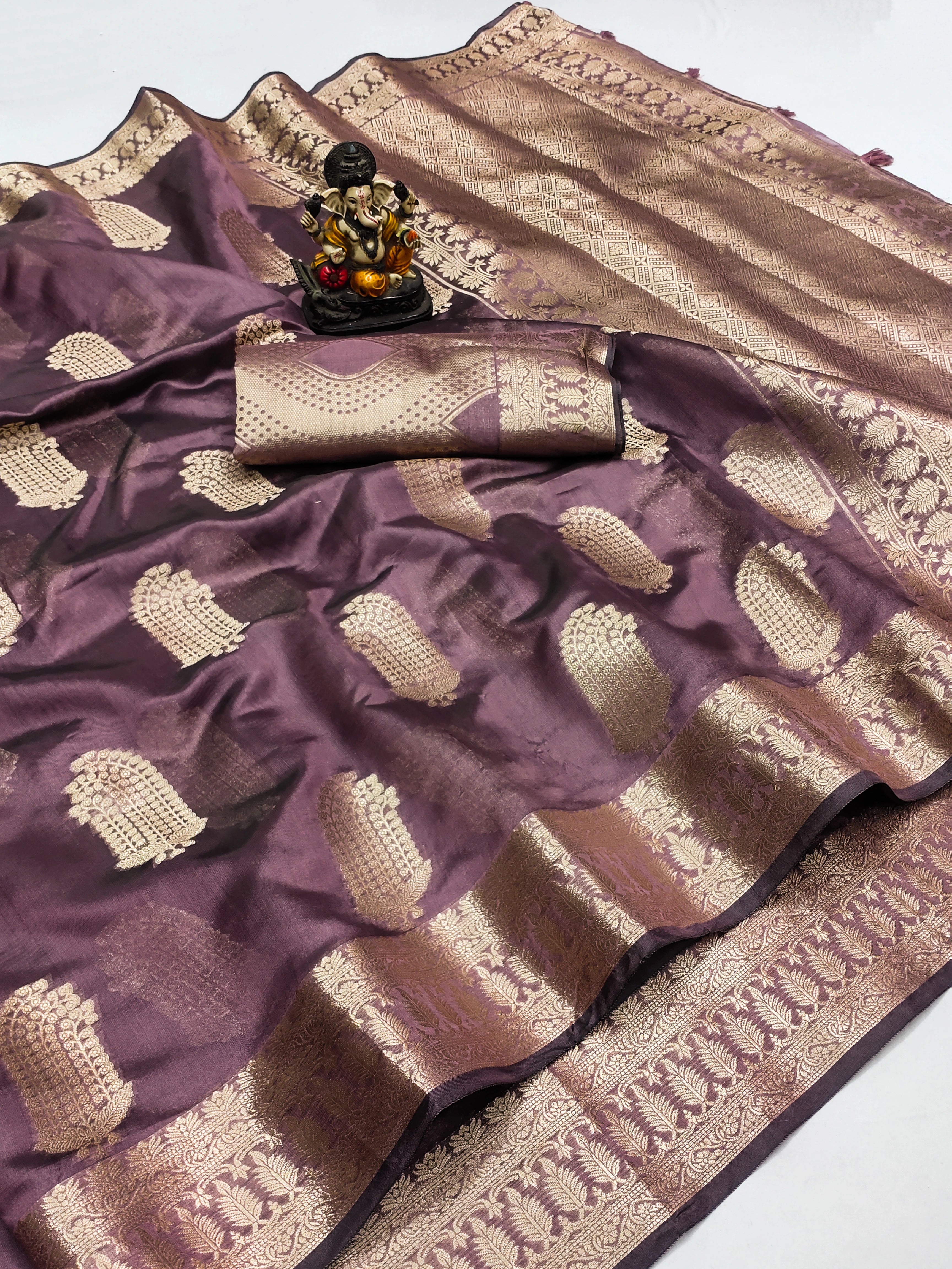 Purple and beige saree with a decorative item on a white background