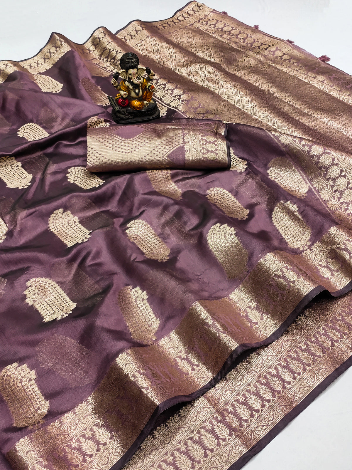 Purple and beige saree with a decorative item on a white background